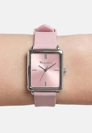 Quadratische pinke Armbanduhr mit silbernem Rahmen und minimalistischen Ziffern, getragen am Handgelenk mit passendem pinken Silikonarmband.
