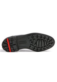 Suola di scarpa in gomma nera con un motivo di grip testurizzato, caratterizzata da un accento rosso sul tallone e un marchio inciso al centro.