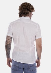 Camicetta bianca a maniche corte in lino leggero, con una texture morbida e colletto, orlo dritto e design minimale.