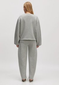 Grijze sweatshirt en bijpassende trainingsbroek van een zachte, textuurstof. Comfortabele pasvorm met verlaagde schouders en recht gesneden broekspijpen.