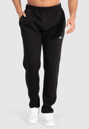 Svarta sweatpants med elastisk midja och sidfickor, med en vit logodetalj på vänster höft. I kombination med vita sneakers.