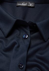 Navy blue button-up shirt made of smooth fabric, featuring a classic collar and contrasting dark buttons with a subtle sheen.