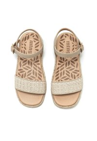 Sandalias de un beige claro con dos correas anchas; una es trenzada y la otra es lisa. Cuenta con una correa para el tobillo ajustable y una plantilla texturizada con un patrón de hojas.