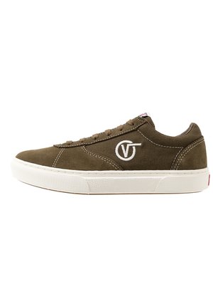 Niski zielonkawy oliwkowy sneaker z białym naszywanym logo po boku, brązowymi sznurówkami i grubą białą, fakturowaną podeszwą.