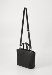 Schwarze Ledertasche mit verstellbarem Riemen, doppelten oberen Griffen, weißen Nähten, rechteckiger Form, glatter Oberfläche und silbernen Hardware-Akzenten.