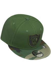 Grüne Baseballmütze mit einem Schirm im Camouflage-Muster, geprägtem "Raiders"-Logo auf der Vorderseite, aus strukturiertem Stoff mit gestickten Details.