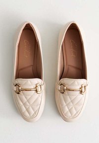 Beiga quiltade loafers med en spänne i guldton. Slät syntetisk material och rund tådesign, med en vadderad innersula.