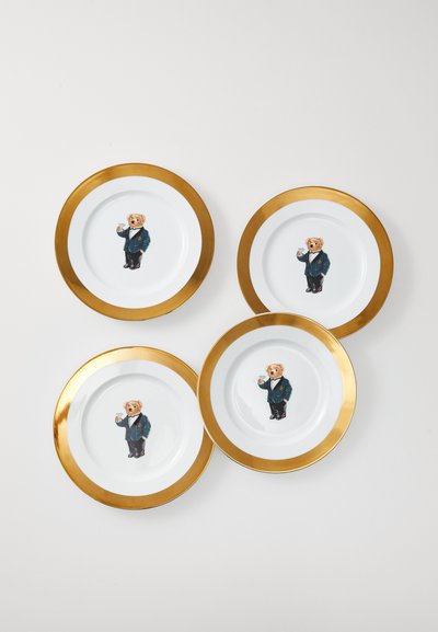Četiri bijele ploče s zlatnim rubovima, svaka s medvjedom u fracu koji drži čašu martini na središtu, raspoređene na bijeloj površini.