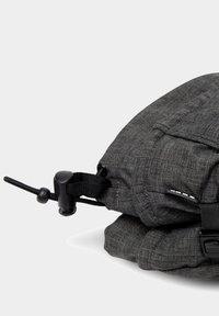 Borsa in tessuto grigio con superficie testurizzata, dotata di chiusura laterale con cordino e tracolla, forma arrotondata e dettagli di cucitura visibili.