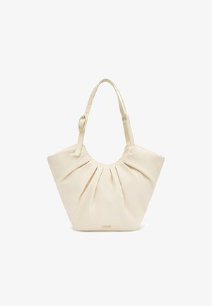 Bolso de cuero color crema con pliegues recogidos, correa ajustable con hebilla dorada y pequeño logo dorado "TOUS" en el centro inferior.