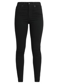 Jeans slim negros de denim, con una cintura alta, bolsillos frontales y pasadores para cinturón. Textura suave sin adornos prominentes.