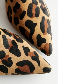 Chaussures à bout pointu à imprimé léopard dans des teintes marron, noir et brun. Matériau doux et texturé avec un design élégant et effilé.