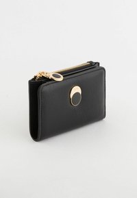 Czarny skórzany portfel o gładkiej fakturze, prostokątnym kształcie, złotych elementach metalowych, zamknięciu na zamek oraz okrągłym akcentem z przodu.