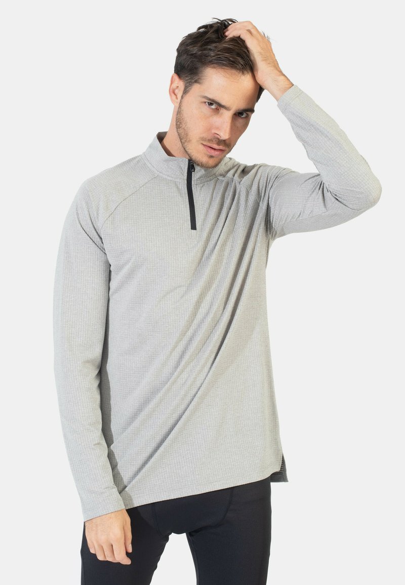Camiseta de manga larga gris claro con cremallera de cuarto, con un patrón texturizado, que presenta una cremallera negra y un corte atlético.