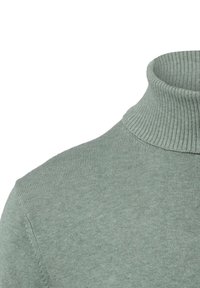 Jasnozielony dzianinowy sweter z golfem, pokazujący ściągaczowy kołnierz i gładką dzianinę na ramieniu i klatce piersiowej.