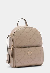Zaino in faux leather beige con motivo a logo in rilievo, forma arrotondata, hardware dorato e una tasca con zip frontale.