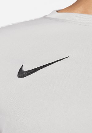 Witte sportshirt met korte mouwen, voorzien van een opvallend zwart Nike-logo op de linkerschouder, met een gladde textuur en een nauwsluitend design.
