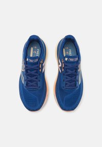 Baskets de sport bleues avec tige en mesh, design à lacets, accents réfléchissants et semelle de confort de couleur claire. Présente le logo "Fresh Foam".