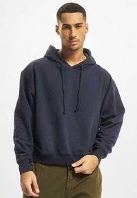 Felpa blu navy realizzata in tessuto morbido, con cappuccio regolabile, tasca a marsupio e polsini a coste. Design semplice e dalla vestibilità rilassata.