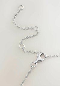 Catena metallica d'argento composta da anelli intrecciati, con chiusura a moschettone e anelli circolari per la chiusura. Texture liscia, design minimalista.