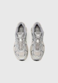 Grey running shoes with a mesh and synthetic upper, featuring a textured design, elastic laces, and a cushioned sole. Subtle branding visible.