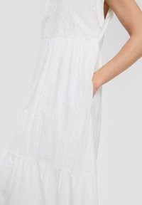 Witte, mouwloze jurk van textured stof met borduurwerk en oogjesdetails. Losse pasvorm met een gelaagde zoom en zijzakken.