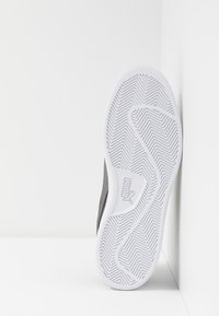 Scarpa sportiva nera con parte superiore texturizzata e suola in gomma bianca con motivo a zigzag e logo Puma.