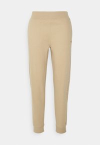 Beige Jogginghosen aus weichem Stoff, mit elastischem Bund, schmal zulaufenden Beinen und seitlichen Taschen, mit dezentem Branding an der Seite.