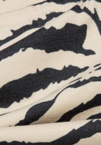 Black and beige fabric featuring a zebra stripe pattern, showcasing a smooth texture with visible stitching and fabric weave detail.