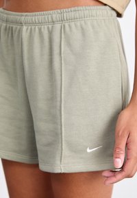 Světle zelené šortky Nike z měkké látky s elastickým pasem, bočními švy a malým bílým logem na levém stehnu.