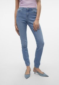 Svetlo modri skinny jeans iz denimske tkanine z visokim pasom, subtilnim bledenjem in petimi žepi, v kombinaciji s svetlo modrimi pointed heels.
