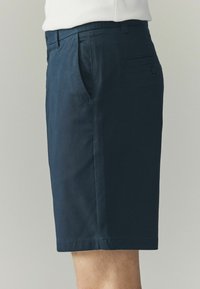 Pantaloni scurți de culoare albastru închis, dintr-un material ușor, cu buzunare laterale, croială dreaptă și un buzunar pe spate cu închidere cu buton.