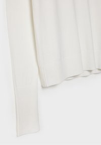 Suéter blanco de punto con puños y dobladillo acanalados, textura suave y un corte relajado. El material parece suave y ligero.