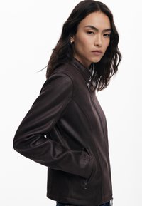Ruskea nahkatakki, jossa on vetoketjullinen etuosa, slim fit -leikkaus, korkea kaulus ja sivutaskut. Sujuva pinta, jossa on minimaalinen yksityiskohtaisuus.