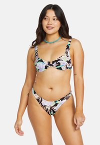 Blommig bikiniuppsättning med svart bakgrund, lätta lila och gröna botaniska mönster, med en strukturerad topp och lågt skurna byxor.