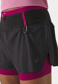 Mustad mustreningud mustad varbadega, millel on külgslõige, pehme võrkmaterjal ja väike logo. Lisatud on aas ja karabiin kinnitamiseks.