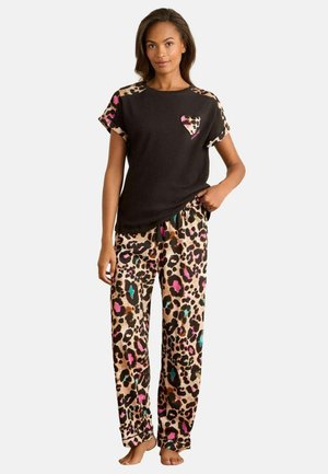 Schwarzes Baumwoll-Top mit kurzen Ärmeln und Akzenten im Leopardenmuster, kombiniert mit locker sitzenden Hosen im Leopardenmuster in Brauntönen, Pink und Teal.