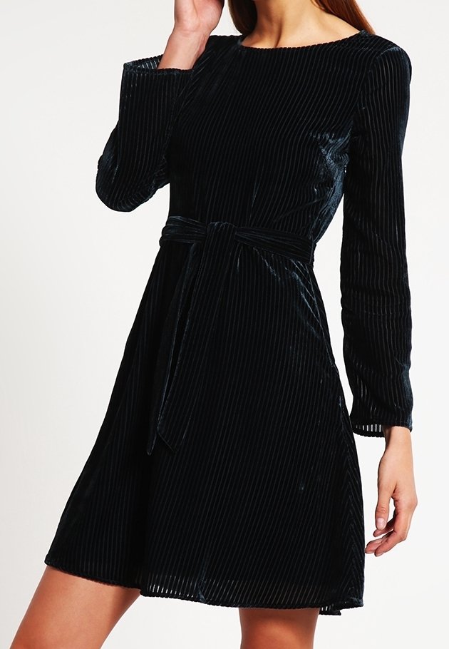 Robe en velours noir à manches longues, texture côtelée horizontale, taille cintrée et ceinture assortie, s'évasant doucement au niveau de l'ourlet.