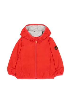 Czerwona dziecięca kurtka z kapturem, szarym wewnętrznym wyścieleniem, zamkiem błyskawicznym z przodu, elastycznymi ściągaczami i okrągłą czarno-pomarańczową naszywką z logo na lewym rękawie.