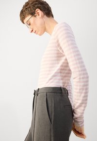 Rožinė ir balta dryžuota ilgomis rankovėmis palaidinė, derinama su pilkomis aukštomis kelnėmis su klostėmis ir šoninėmis kišenėmis. Elegantiškas dizainas ir fasonas.