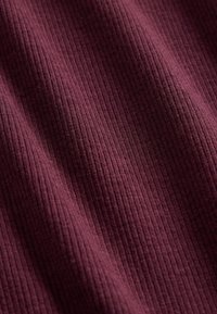 Tissu texturé en bordeaux profond, présentant un motif côtelé avec une sensation douce et légèrement extensible, affichant de légères variations de lumière et d'ombre.