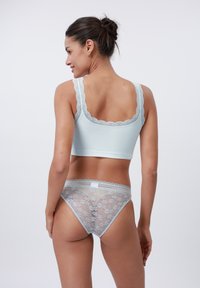 Top scurt cu dungi de culoare bleu deschis, cu detalii din dantelă și chilot transparent din dantelă asortat, cu modele florale. Vedere din spate care evidențiază detaliile delicate.