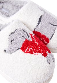 Pantofole bianche pelose con un design testurizzato, decorate con un cane grigio e dettagli in rosso. Materiale morbido con stile a chiusura dietro.