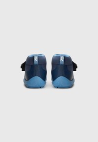 Ein Paar navy und hellblau gefärbte Babyschuhe mit strukturierten Sohlen, von hinten auf einem hellgrauen Hintergrund gezeigt.