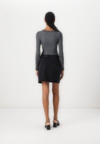 Haut long à manches gris côtelé avec des accents en dentelle, associé à une mini-jupe en denim noire avec des poches arrière et un ourlet droit.
