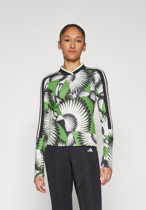 Langslijf sporttop met een groen en zwart vogelprint, met een v-hals, contrasterende crèmekleurige kraag en witte zijstrepen.