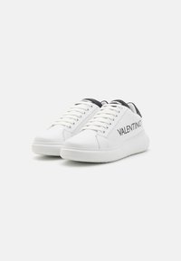 White leather sneakers with black accents, round toe, flat sole, and lacing system. Features brand name "VALENTINO" on the side.