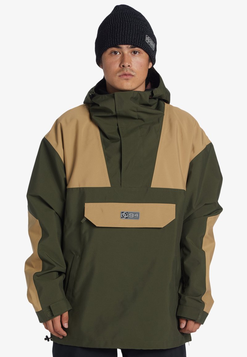 Chaqueta tipo pullover en verde y topogén, con capucha, bolsillo frontal y logo. Presenta un corte relajado y una tela duradera, adecuada para uso al aire libre.