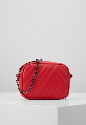 Kleine rode doorgestikte crossbodytas met zwarte kettingriem, rechthoekige vorm, weergegeven op een wit oppervlak tegen een lichtgrijze achtergrond.