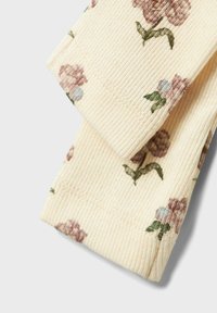 Tissu crémeux à côtes avec un motif floral dans des nuances de rose et de bleu, présentant des feuilles vertes. Deux pièces pliées empilées l'une sur l'autre.